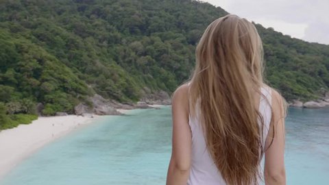 Woman stands on the top of mountain peak with sea and tropical island view and enjoy the beautiful outdoor landscape. Travel, freedom, vacation and happiness concept. Adlı Stok Video