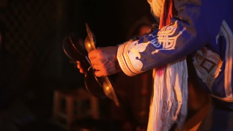 Tight shot of man in Moroccan dress playing arabic doumbek, darbuka.