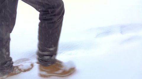 Walking feet in boots on a winter landscape in slow motion, a winter walk in the mountains, holiday vacation tourism, falling snow