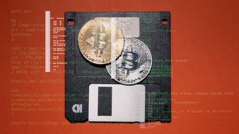 Source code scrolling over a scene: throwing a golden and a silver bitcoin (digital crypto currency) on an obsolete floppy disk (memory support), and picking both.
