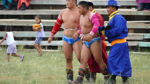 Telmen sum, Mongolia - July 15, 2017: Mongolian national holiday Naadam. Competition wrestlers in the open stadium. Two heroes try to grab and knock each other. Editorial use.