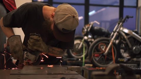 Man works with electric wheel grinding on steel structure with sparks
