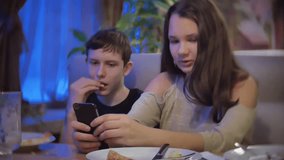 Group of friends sitting at cafe and taking smartphone. children teens eat pizza in cafe slow motion video indoors