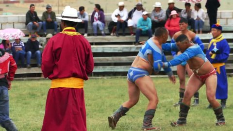 Telmen sum, Mongolia - July 15, 2017: Mongolian national holiday Naadam. Competition wrestlers in the 

open stadium. Two bogatyrs try to grab and knock each other. Editorial use.