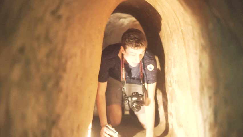 White young man and woman crawl through underground Cu chi tunnels from Vietnam War