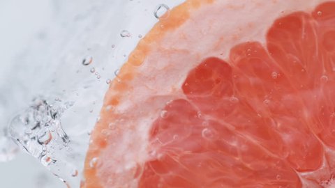 Halved pink grapefruit falling in water. Shot with high speed camera, phantom flex 4K. Slow Motion.