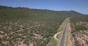 4K sunny summer morning aerial footage of red brown sandstone Waterberg Plateau Park rocky wall and plateau with savanna green trees area around it in central-northern Namibia, southern Africa