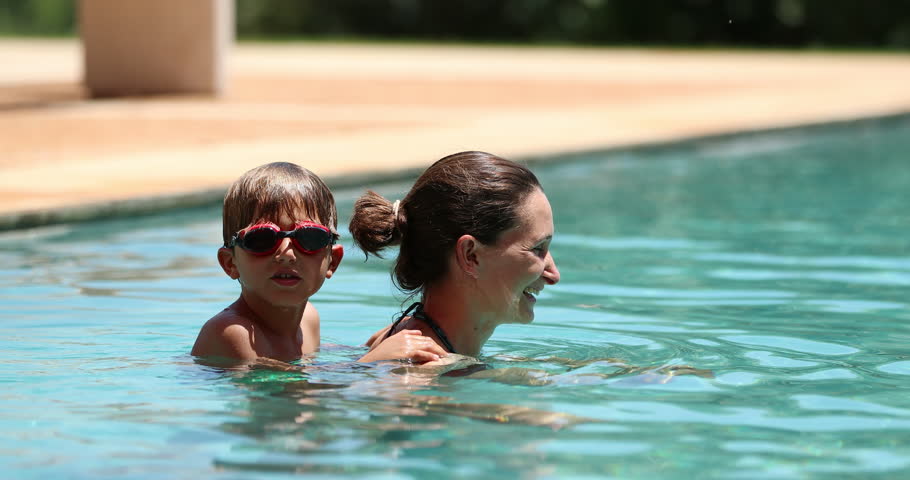 Child and mother at the swimming pool in 4k resolution. Candid slow-motion clip of child holding himself into his mom at the pool | Shutterstock HD Video #1008758126