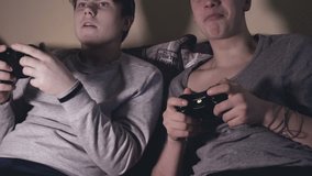 Two friends (guys) play video game console, have fun, laugh, hold the joystick.