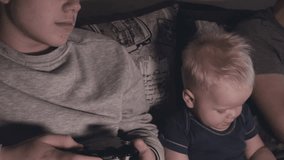 Guys and baby boy play video game console, have fun, laugh, hold joystick.