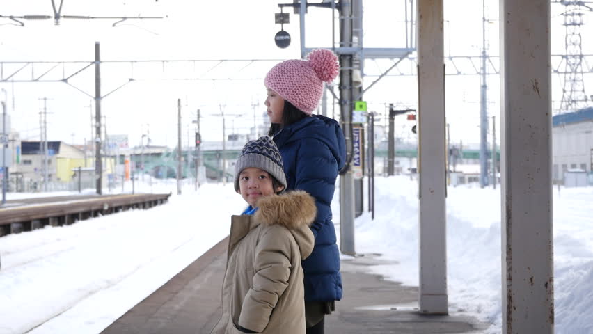 Asian children waiting express train on railway station platform,winter travel concept