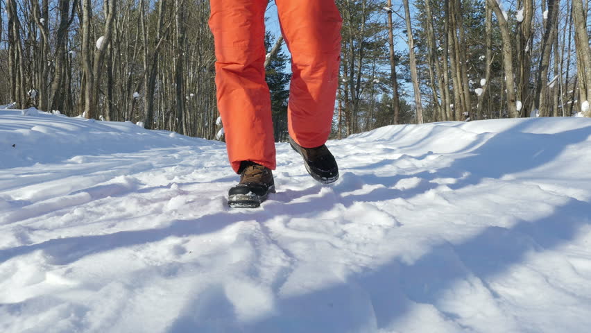Male feet walking through the snow in winter forest, Front view, 4k steadicam shot