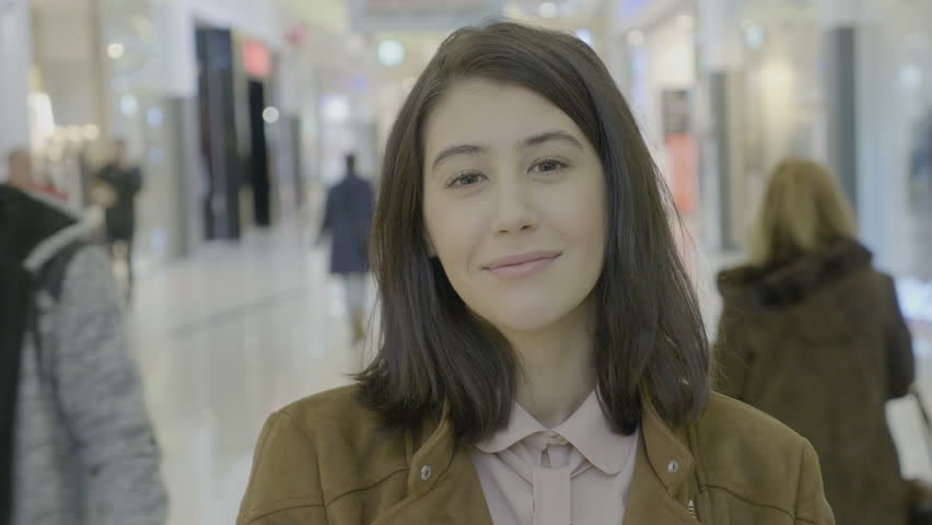 Portrait of a happy angelic female entrepreneur looking sides and smiling at the camera before starting her shopping in the mall center