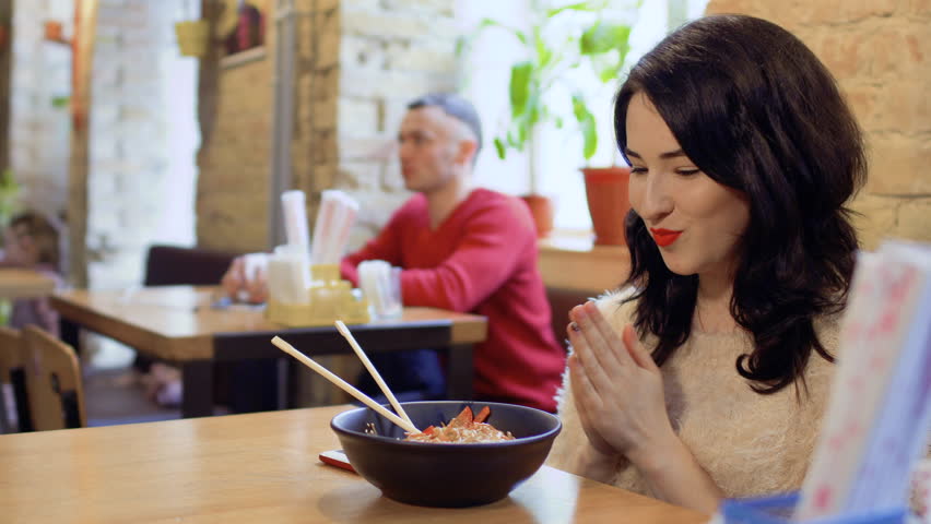 Bautiful woman tries a tasty traditional dish in korean restaurant
