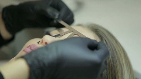 Microblading procedure. Master marks out customer's eyebrows.