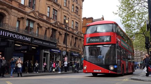 LONDON, ENGLAND, UNITED KINGDOM - APRIL, 2017: Red famous double-decker buses,small classic car driving on Charring Cross Road in London city past Leicester  Square underground station and Hippodrome