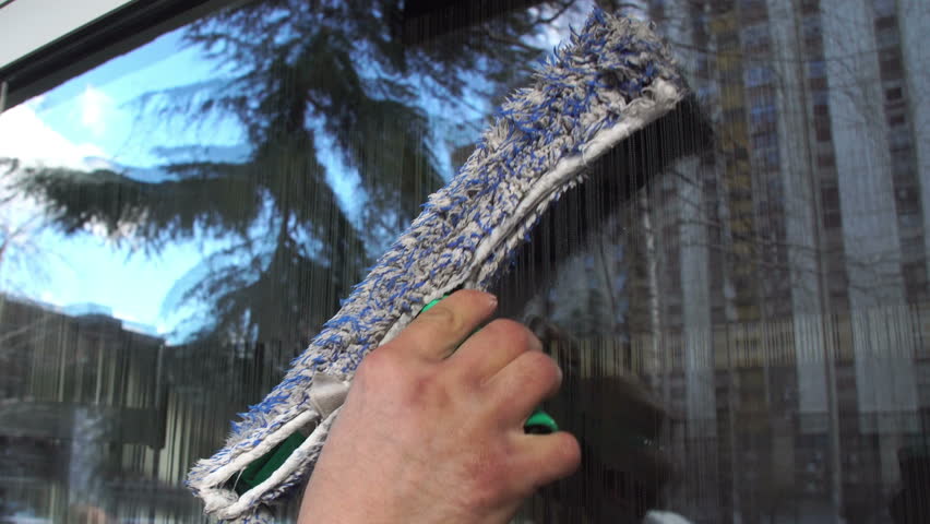 Cleaning the window. A young man cleans and polishes windows with a sponge Royalty-Free Stock Footage #1008810788