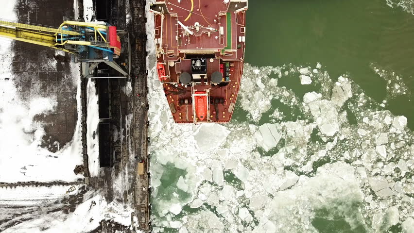 Aerial view. The big ship sails through the sea ice in the winter, close-up