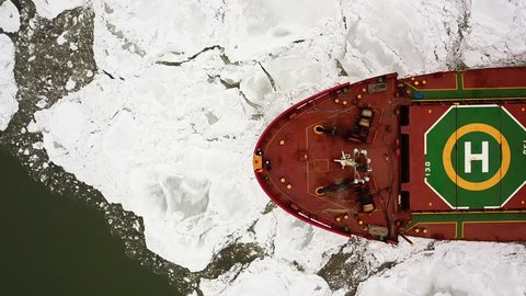 Aerial view. The big ship sails through the sea ice in the winter, close-up