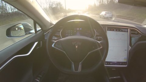 TESLA AUTONOMOUS CAR, MARCH 2018: LENS FLARE: Breakthrough autonomous vehicle navigates and steers itself down freeway on sunny evening. Futuristic driverless Tesla car speeding along sunlit motorway.