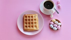 Pouring chocolate on waffle. Cup of coffee on pink background.