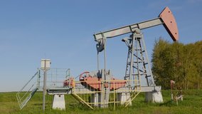 Operating oil and gas well in oil field, profiled against the blue sky