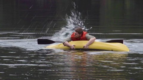 A man struggles in the water with his tipped kayak.