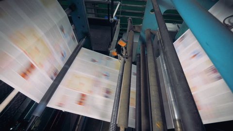 Conveyor with numerous freshly printed newspapers. 4K.