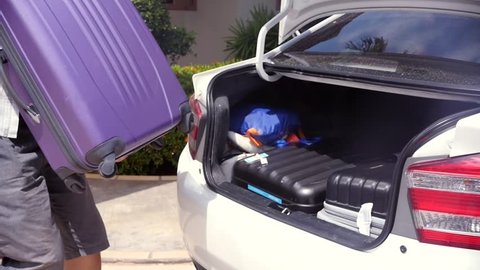 The man puts the third big heavy suitcase with things in the trunk of the car. slow motion, 1920x1080, full hd