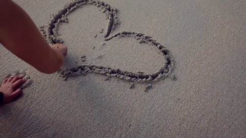 Happy girl draws on a sandy beach heart, makes a confession. slow motion, 1920x1080, full hd