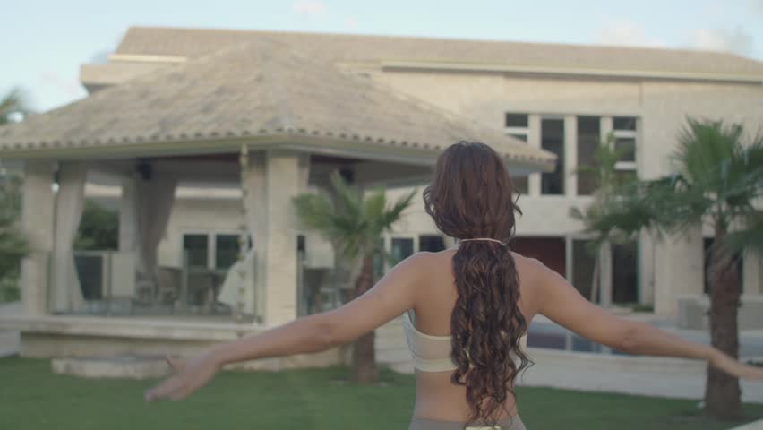 Young girl doing yoga in front of her luxury home villa