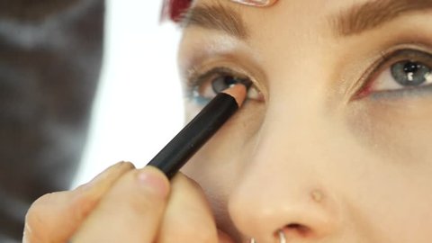 Professional make-up artist applying eyeliner on eye. makeup and fashion concept