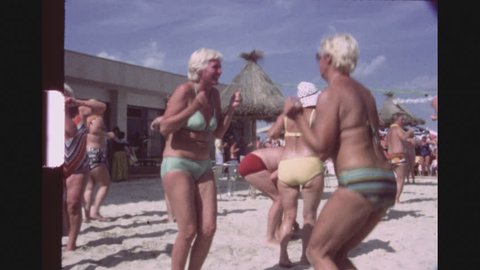 SPAIN, MALLORCA, JULY 1983. A Group Of Caucasian Tourists Participitating In A Chicken Dance Contest At A Beach Bar, Clapping, Dancing And Shaking.
