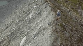 Drone point of view of young woman hiking on the ridge of a mountain in Valais Canton, Switzerland. People travel outdoor concept, aerial view 4K