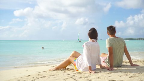 Young couple on white beach during summer vacation. Happy lovers enjoy their honeymoon at exotic island
