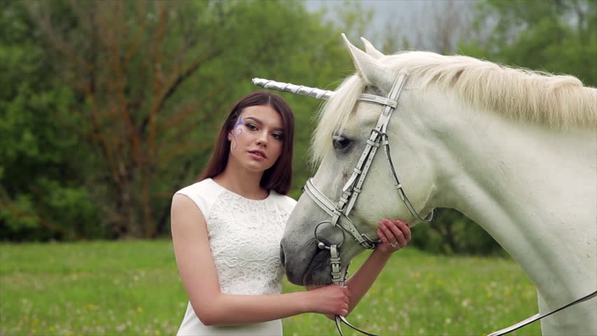 Girl with long hair gently leans her head on the unicorn