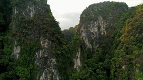 AERIAL. Amazing cinematic style video of huge mountains and rain forest at south of Thailand. Drone flight through peak. Sun flares behind mountains. Two birds flight near quadrocopter.
