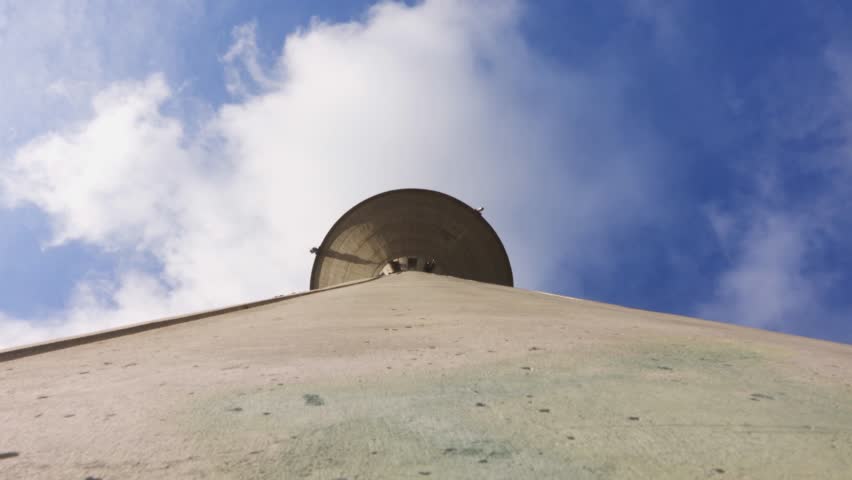 Water tower against a blue sky with clouds closeup.