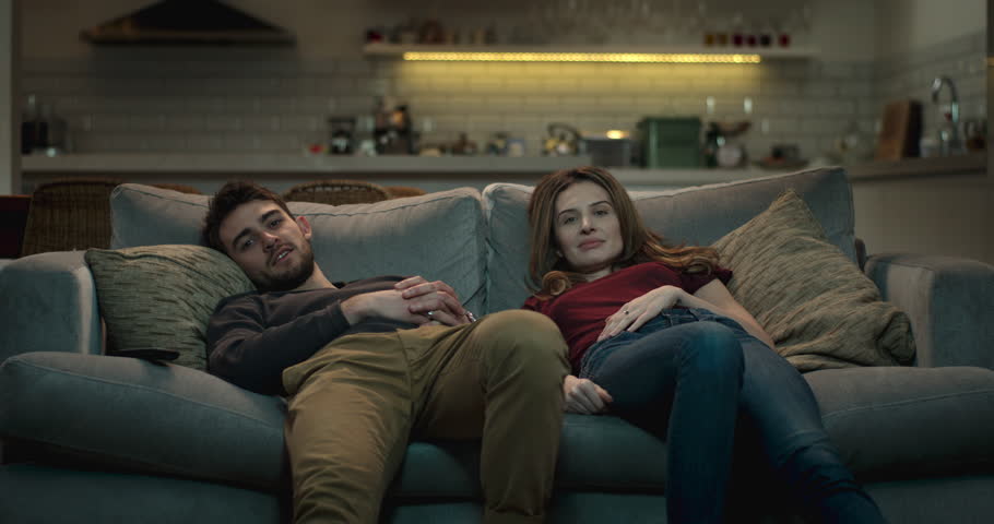Relaxed couple slump on the couch in a cozy living room watching tv. | Shutterstock HD Video #1008851261