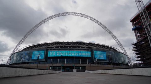 London, United Kingdom / March 8, 2018 : Timelapse of Wembley stadium on non-match-day showing advertisement on the stadium screen. Windy day created fast moving cloud over the stadium.