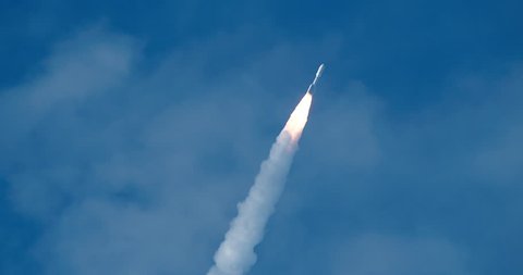 Space Rocket flying against deep blue sky with bright flames and dense exhaust smoke form the solid rocket boosters. 4K at 120 fps slow motion.