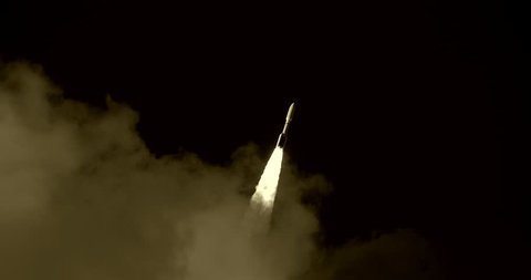 ICBM missile Space Rocket emerging from behind clouds and flying through black sky with bright flames and a nice trail of white exhaust smoke.