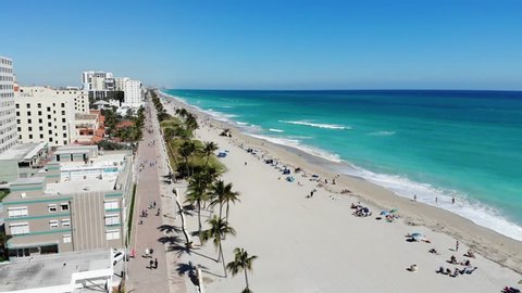Aerial view of Hollywood Beach, Florida, near Miami Beach. The view encompasses the luxury hotel chains along the waterfront. The boardwalk and people enjoying the beach are visible.
