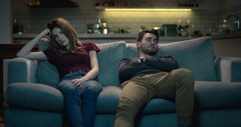 Frustrating relationship - couple at home sitting on a sofa struggling with each others company.