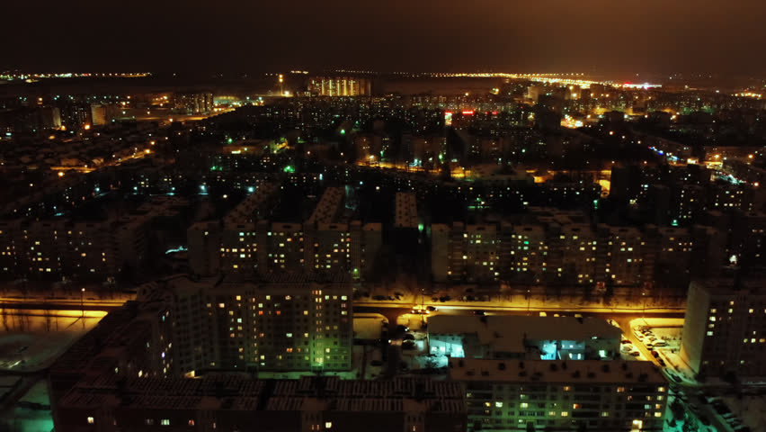 Aerial flight shot above russian night city lights. Cold evening winter town with old soviet buildings. Downtown cityscape