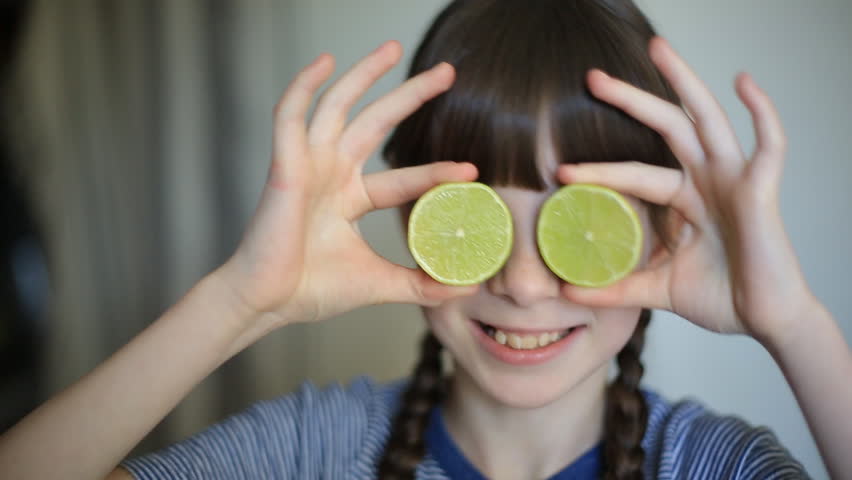 little girl holding halves of green lime at her eyes. Healthy Happy