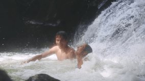 Happy beautiful couple swimming under waterfall relaxing under stream water in a tropical jungle. slow motion. 1920x1080