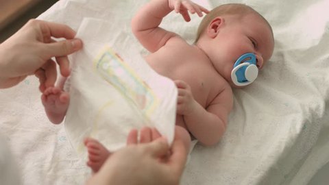 Careful mother changes diapers to her newborn baby