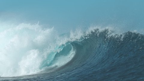 SLOW MOTION, CLOSE UP: Stunning barrel wave shines brightly in the pretty summer sunlight. Huge tropical wave coming from the endless ocean rushes towards empty beach. Breathtaking natural wonder.
