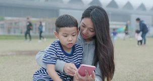 Mother and son look at smart phone at outdoor park